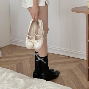 Dettaglio di Mary Jane nere stile balletto con calze con fiocco scozzese e scarpe bianche