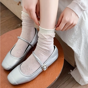 Silver Mary Jane shoes with light pink ruffled socks on a wooden stool background
