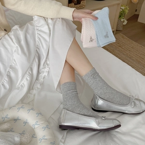 Three pairs of twist-knit socks in grey, pink, and blue with metal bow accents