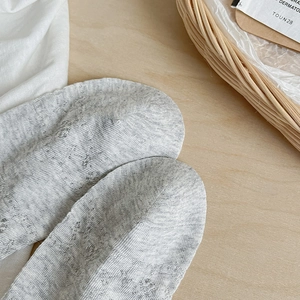 Close-up of grey lace hollow knitted socks with delicate mesh pattern on wood background