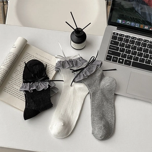 Détail de chaussettes en coton avec bords à volants et rubans à nœuds délicats