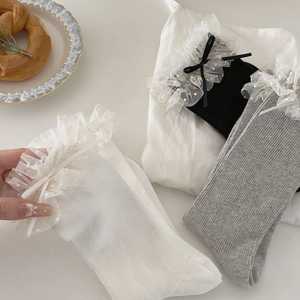 Détail des poignets à volants avec mesh à pois et nœuds en satin sur les chaussettes