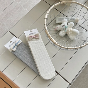 Detail of girls' knit crew socks featuring delicate lace trim and soft ribbon bows