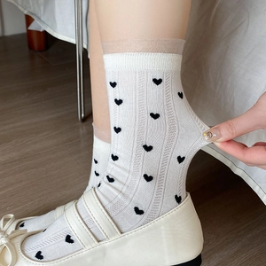 Détail de chaussettes blanches à cœurs noirs avec bordure en tulle et grande élasticité