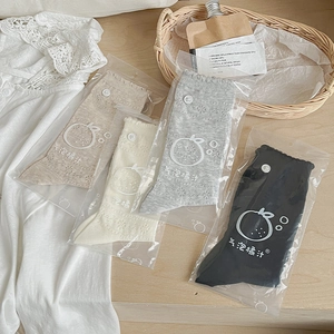 Detail of four pairs of lace socks with button decor in neutral beige, grey, and black