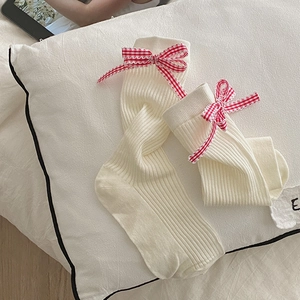 Dettaglio di calze a coste crema con un grazioso fiocco a quadretti bianco e rosso