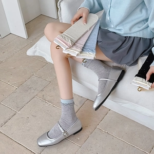Detail of colorful ribbed cotton crew socks paired with stylish silver Mary Jane shoes