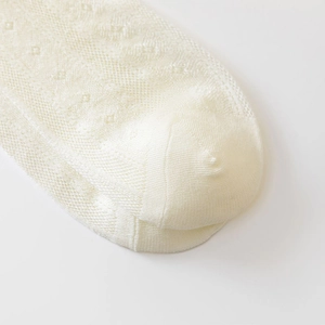 Detail of cream white mesh socks showing hollow point knit and diamond patterns