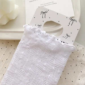 Close-up of white lace socks with floral mesh pattern and scalloped edge on display card