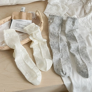 Close-up of floral lace mesh socks with button detail in beige and light gray colors