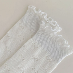 Détail de chaussettes blanches style ballet avec bords volantés et motif jacquard
