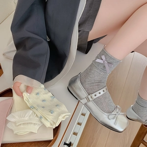 Detail of grey bow socks paired with silver Mary Jane shoes and white floral lace socks