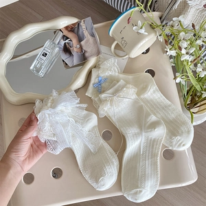 Détail de chaussettes Lolita blanches avec volants en dentelle et nœuds sur une chaise