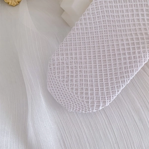 Detailed macro view of white lace mesh fabric with delicate diamond weave pattern