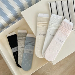 Detail of six-color hollow knit crew socks with delicate dot pattern in a white tray