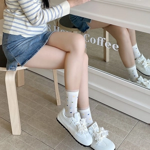 Détail de chaussettes blanches avec broderies de cœurs colorés et bordures en dentelle