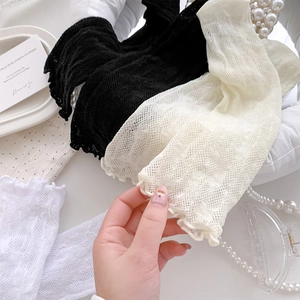 Close-up of sheer lace mesh floral socks with ruffled edges in black, cream and white
