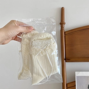 Détail de chaussettes Lolita en dentelle beige avec nœuds dans un sachet zippé