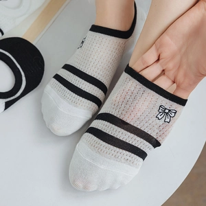Détail de la chaussette en résille blanche montrant le bord élastique noir et le tissu