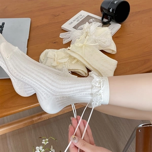 Gros plan détaillé de chaussettes blanches Lolita en dentelle avec nœuds sur bois