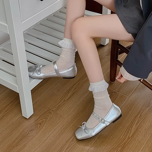Silver Mary Jane flats with bow detail and adjustable strap paired with lace socks