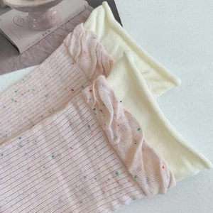 Detail of pink crew socks with colorful dots and beige ruffled lettuce edge cuffs
