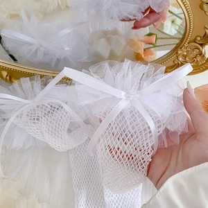Close-up of white lace mesh stockings with tiered ruffles and satin bow in Lolita style