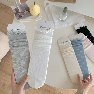 Détail de chaussettes style ballerine avec nœuds ajourés et bords ondulés délicats