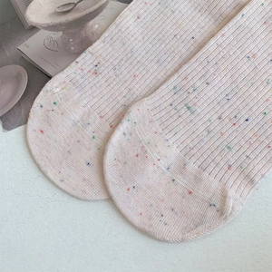 Detail of cream speckled knit socks featuring colorful dots and a ribbed texture finish