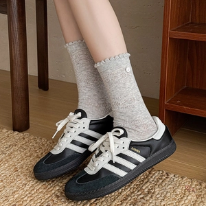 Lace trim mesh socks paired with classic black and white sneakers in a cozy home setting