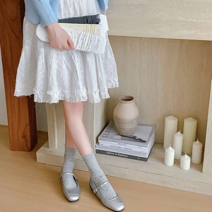 Detailed view of grey sheer polka dot crew socks styled with silver Mary Jane shoes
