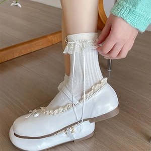 Détail de chaussettes Lolita blanches avec dentelle et nœuds en ruban et chaussures Mary Jane