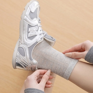Close-up of silver metallic mesh sneakers paired with light grey glittery mesh socks