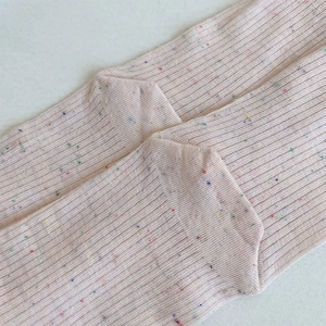 Close-up of pink knit socks with colorful confetti yarn dots and ribbed texture