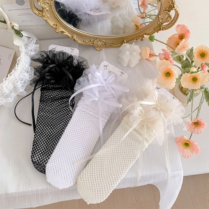 Detail of lace ruffles and ribbon bows on sweet Lolita style mesh crew socks for women