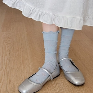 Détail de chaussettes bleu clair avec motifs nœuds roses et bords à volants sur bois