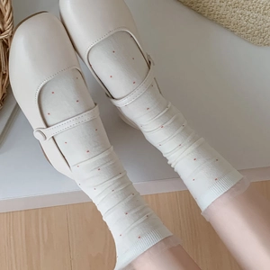 Close-up of cream Mary Jane shoes with white and red polka dot lace-trimmed socks