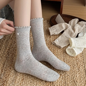 Detail of lace floral pattern socks with decorative buttons and ruffled edges