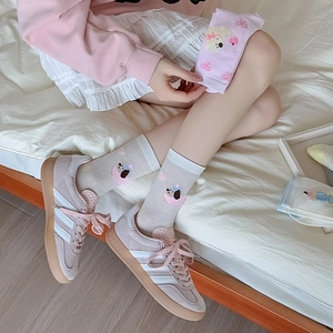 Close-up of pink suede sneakers with cartoon dog embroidery on light mesh socks