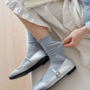 Détail de chaussettes bleues à motifs nœuds et bords volantés avec des Mary Janes