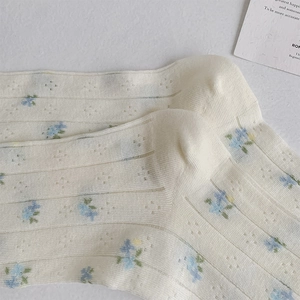 Detailed macro view of cream floral socks with breathable vertical knit and blue flowers