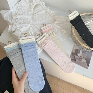 Detail of colorful speckled knit socks in various soft tones on a light wood surface