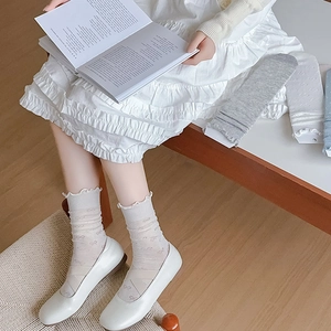 Détail du motif nœud et bord volanté sur chaussettes mi-mollet couleur crème
