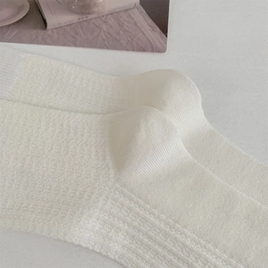 Gros plan de chaussettes blanches en maille côtelée montrant la texture fine en coton doux
