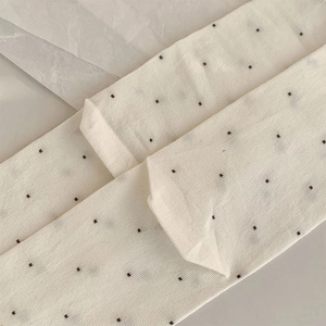 Detailed texture of white lace mesh socks with delicate brown polka dot patterns