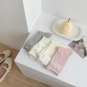 Close-up of four assorted gray and white cotton socks with bow and floral lace details