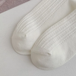 Vue macro de chaussettes en maille blanche avec rayures verticales et détails de couture