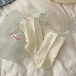 Vue détaillée de chaussettes en résille crème avec motifs cœur et revers à volants