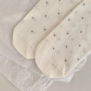 Close-up of cream crew socks with brown polka dots and vertical ribbed texture detail