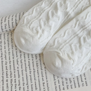 Detailed macro view of white cable knit socks with vintage openwork lace pattern